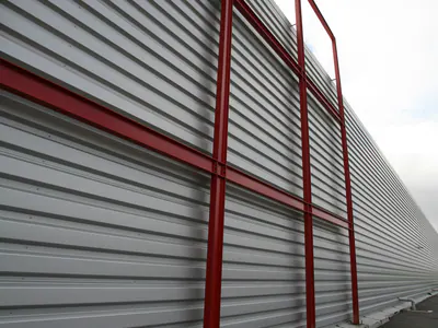 Red steel columns along a metal-clad warehouse wall