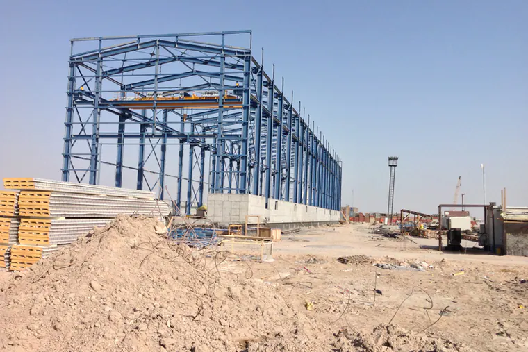 Tall blue steel frame beside mounds of earth and stacked panels