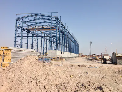 Tall blue steel frame beside mounds of earth and stacked panels