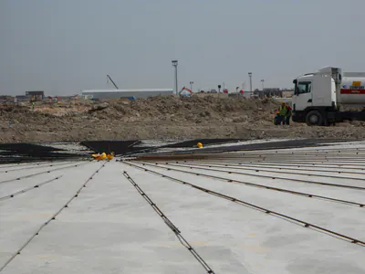 Concrete slab with reinforcing bars laid radially on it, a truck at the edge of the site