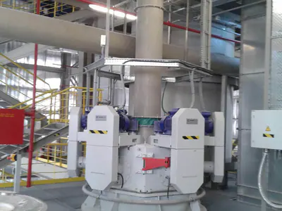 Processing machine with blue motors below a large vertical duct, in a plant hall