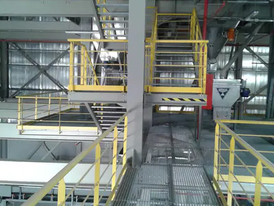 Steel walkways and stairs with yellow handrails inside a plant