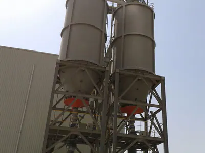 Twin silos on a steel support tower beside a plant building