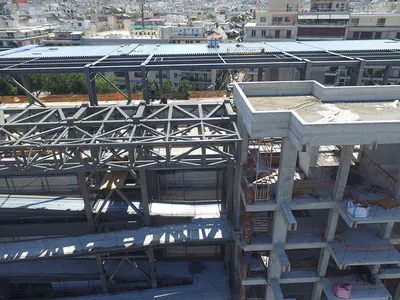 Steel trusses beside the concrete frame of a building under construction