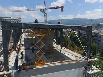 Steel frame on a building roof with a tower crane, workers on top