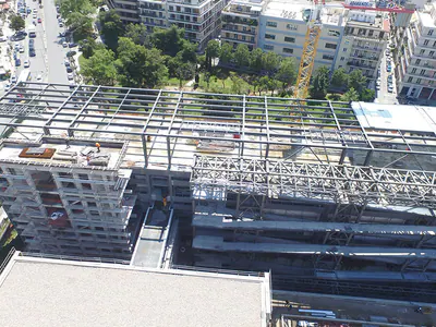 Steel roof trusses along a building under construction, from above a street