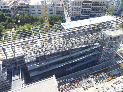 Steel roof framing and trusses along a building, aerial view over treetops