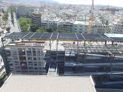 Building under construction with steel roof framing, the city beyond
