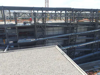 Sloping ramps and braced steel frames inside a building shell, seen across a flat roof