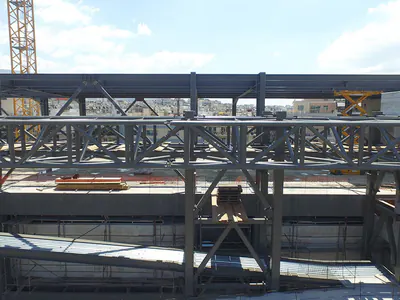 Steel roof trusses above floor beams, a tower crane behind