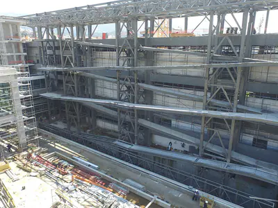 Multi-level steel frame inside a building shell, scaffolding at the sides