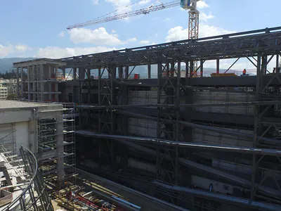 Steel frame of a large building under construction beneath a tower crane