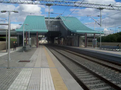 Railway station platforms and tracks with two curved blue-green roof canopies