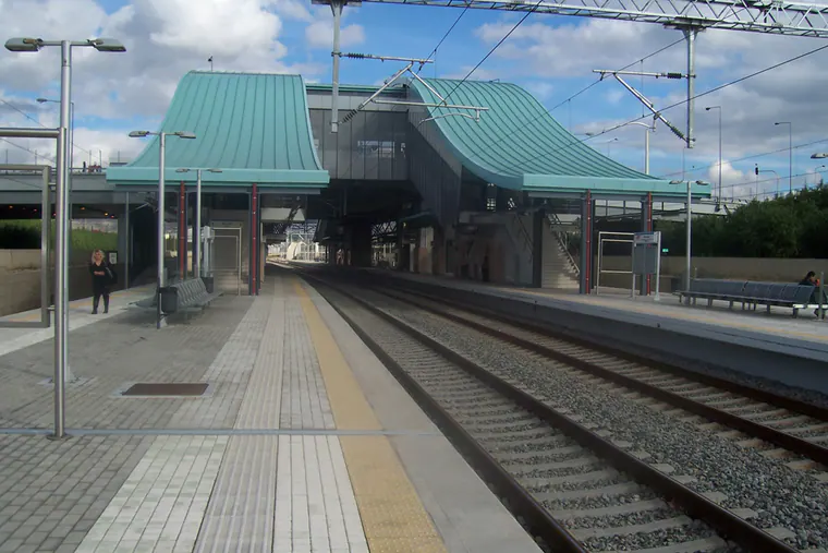 Railway station platforms and tracks with two curved blue-green roof canopies
