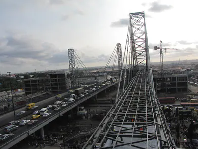 Long steel truss structure above a busy road, under construction