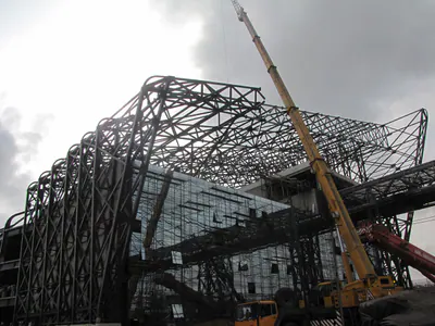 Mobile crane beside a large curved steel space frame