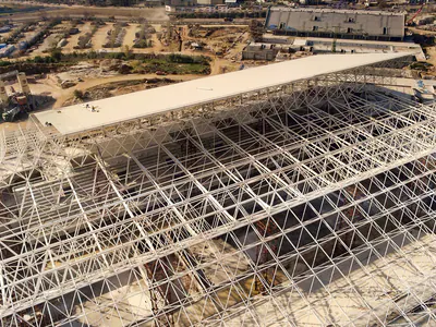 Steel space-frame roof being assembled over tiered stands, aerial view