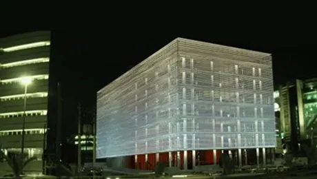 Cube-shaped building with a glowing striped facade at night