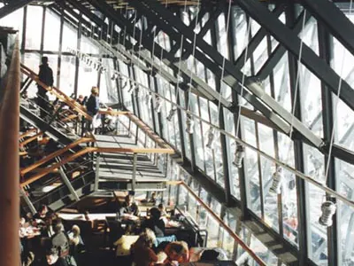 Interior with slanted steel columns and tall windows, people at tables