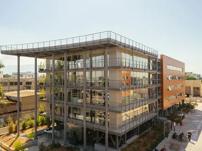 Multi-storey block with a steel frame and orange side walls, a landscaped courtyard in front