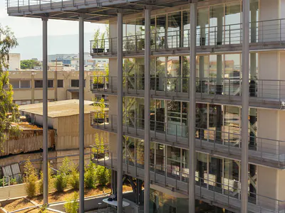Multi-storey building with slender steel columns, a roof canopy and planted balconies