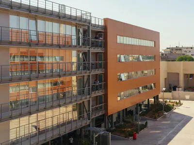 Multi-storey building with steel balconies and an orange-clad end wall