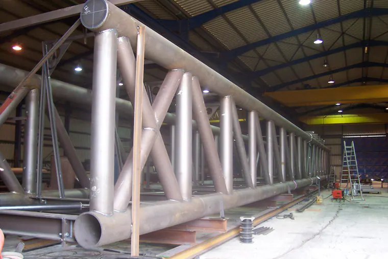 Tubular steel truss under fabrication in a production hall