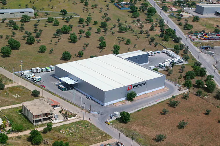 Logistics warehouse with a white roof and parked box trucks, aerial view