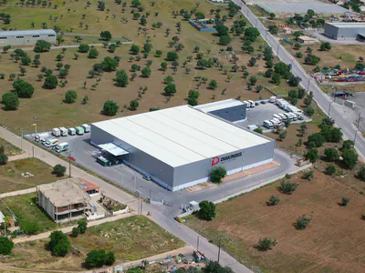 Logistics warehouse with a white roof and parked box trucks, aerial view