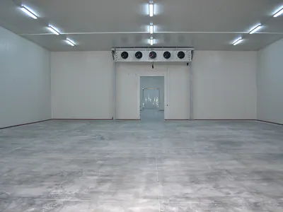 Empty cold room with a ceiling-mounted cooling unit above the door