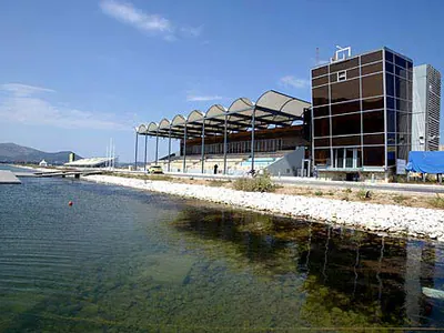 Grandstand with a sawtooth roof and a glazed tower beside the water