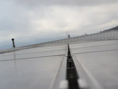Χαμηλή λήψη κατά μήκος του κενού ανάμεσα σε φωτοβολταϊκά πάνελ, κάτω από συννεφιασμένο ουρανό