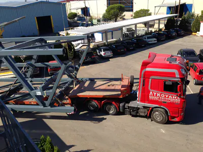 Large grey steel truss loaded on a red lorry in a yard