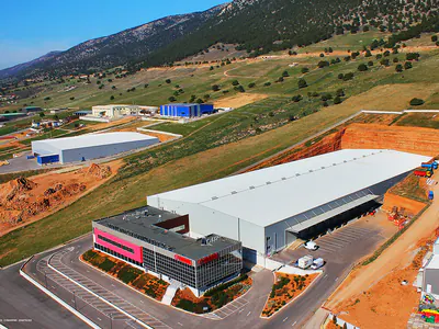 Long warehouse with an office block at one end, hillside behind