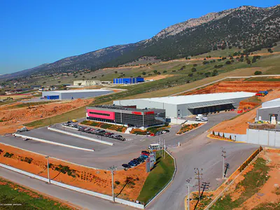 Warehouse and office block beside open land, mountains behind