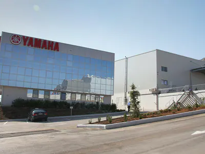 Glazed office building with the Yamaha sign, next to a warehouse