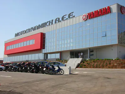 Glass-fronted office building with the Motodynamiki and Yamaha signs, motorcycles parked in front