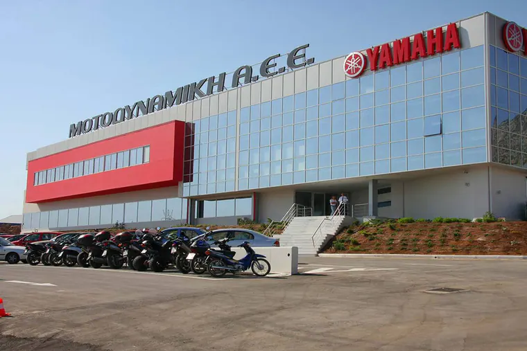 Glass-fronted office building with the Motodynamiki and Yamaha signs, motorcycles parked in front